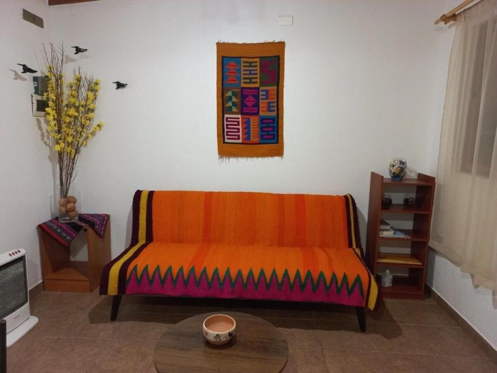 圣佩德罗·德·阿塔卡马Casa Sutar Las Higueras的客厅里一张橙色的沙发,配有桌子