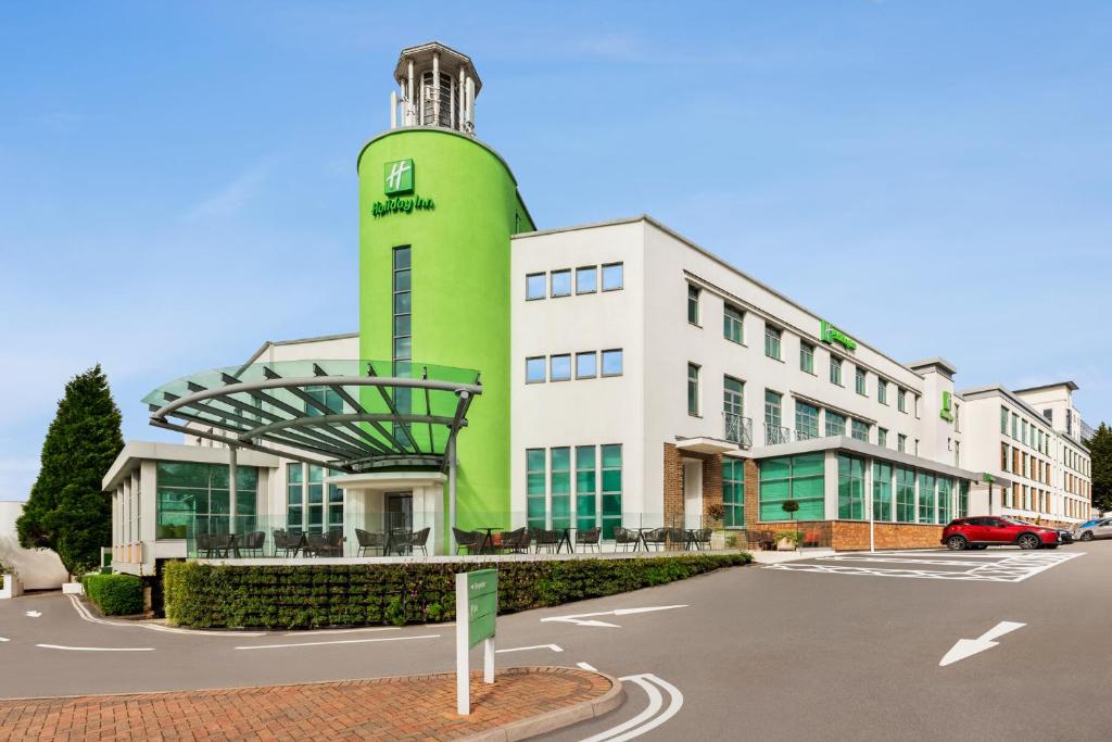 比肯希尔Holiday Inn Birmingham Airport - NEC, an IHG Hotel的停车场内一座带钟楼的绿色建筑