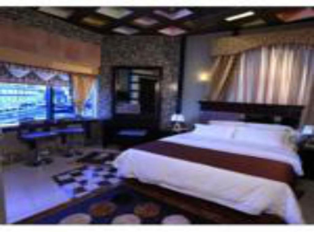 科威特宽敞套房公寓式酒店的一间卧室配有一张床、一张书桌和一台电视