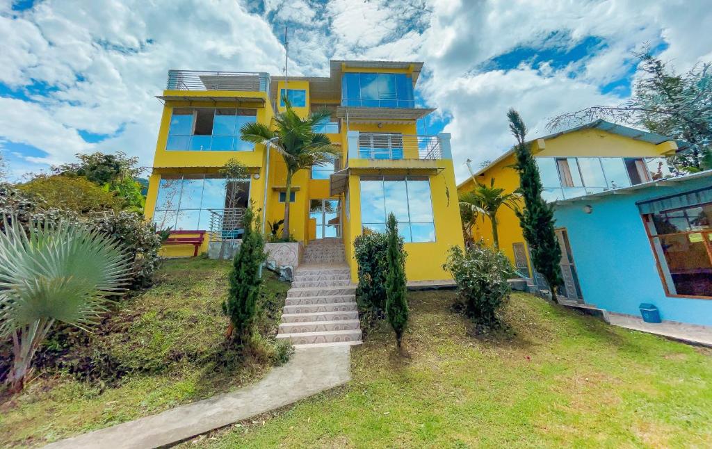 ChachagüíHOTEL PANORAMA SOL的黄色的房子,设有蓝色的窗户和楼梯