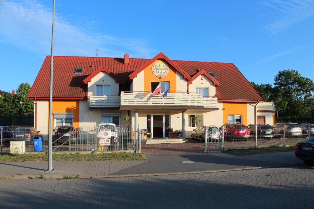 格里兹鲍Aqua Villa Grzybowo Pension的红色屋顶的橙色和白色建筑