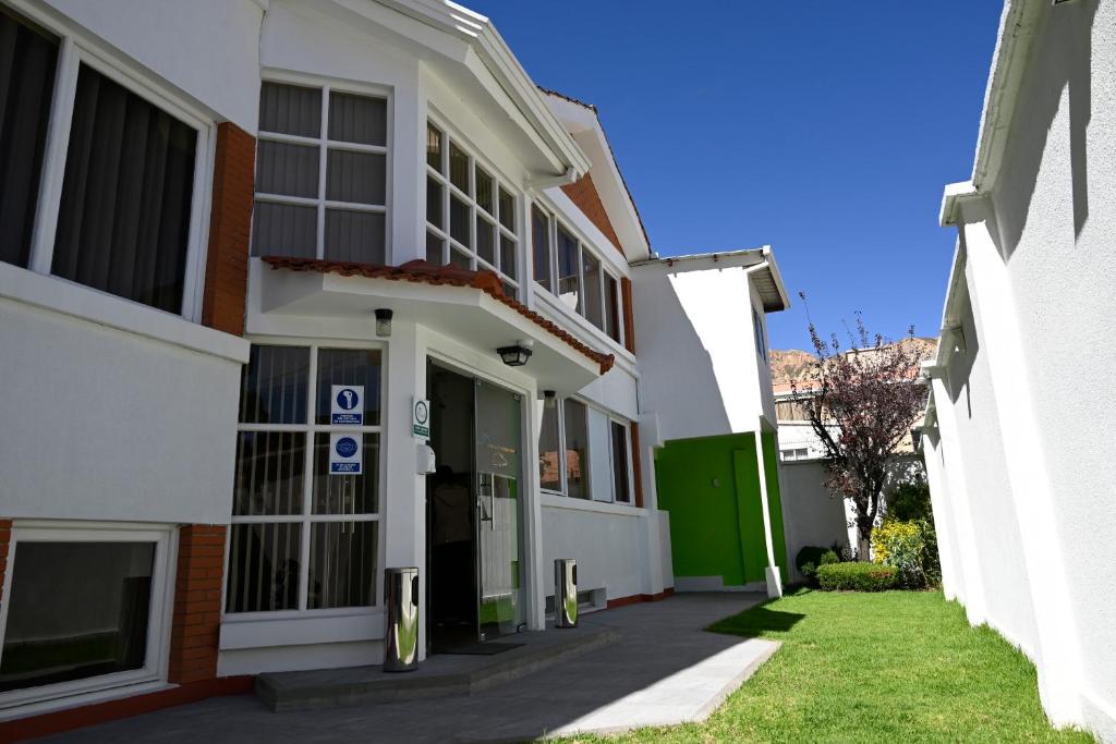 拉巴斯佐纳苏尔玻利维亚客房套房旅馆的白色的建筑,有绿门和草地