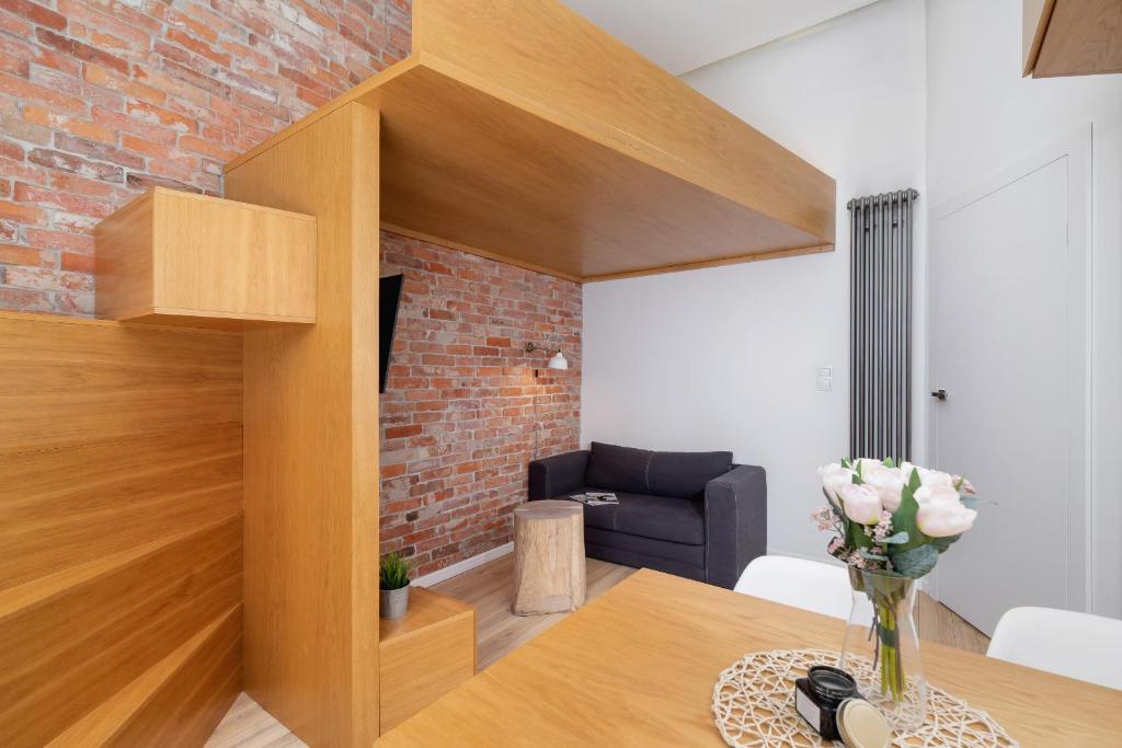 克拉科夫Apartment with Mezzanine - Ariańska 14 by Renters的客厅配有桌子和砖墙