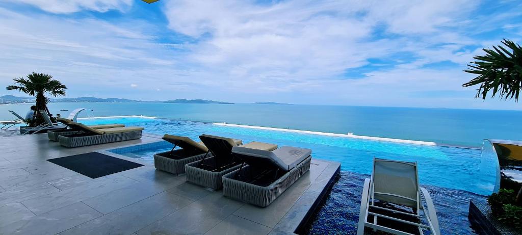 乔木提恩海滩Seaview Beachfront Skypool Rooftop Copacabana Jomtien Condo的水边的游泳池,设有沙发和椅子