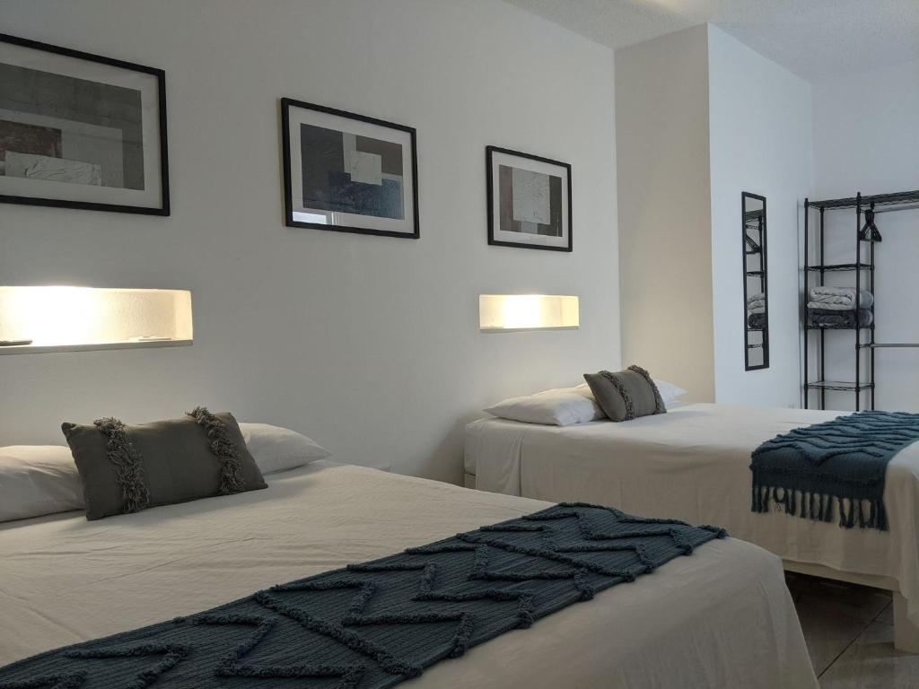 坎昆Hermoso departamento en Cancún YaxBahia 3的一间设有两张床的客房,墙上有两张照片