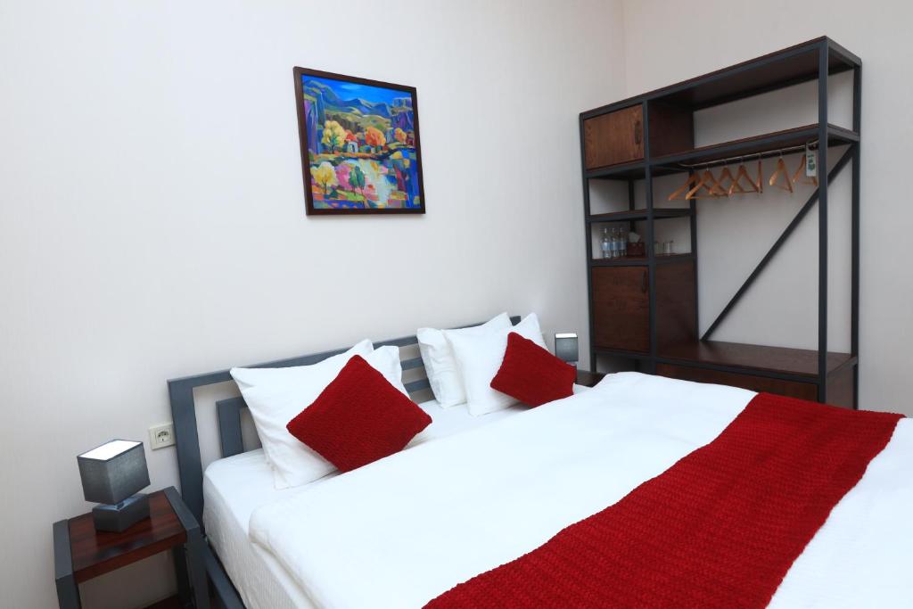 久姆里Syune Mini Hotel的一间卧室配有两张带红色枕头的床