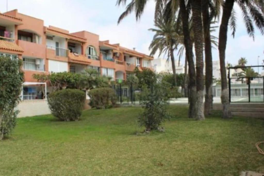 滨海罗克塔斯Entremares estudio a 150 metros playa的一座棕榈树的大型公寓楼,位于庭院内