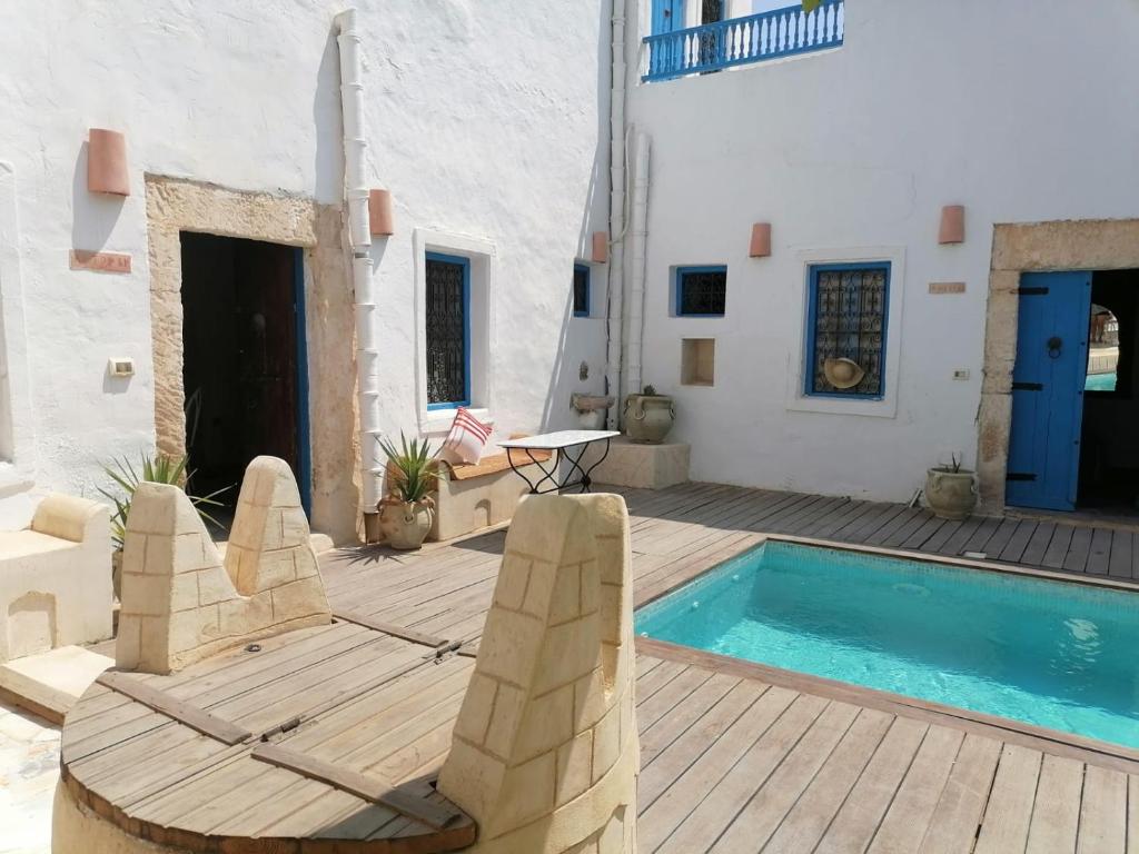 乌姆苏克Dar Michèle Djerba的庭院设有游泳池、椅子和桌子