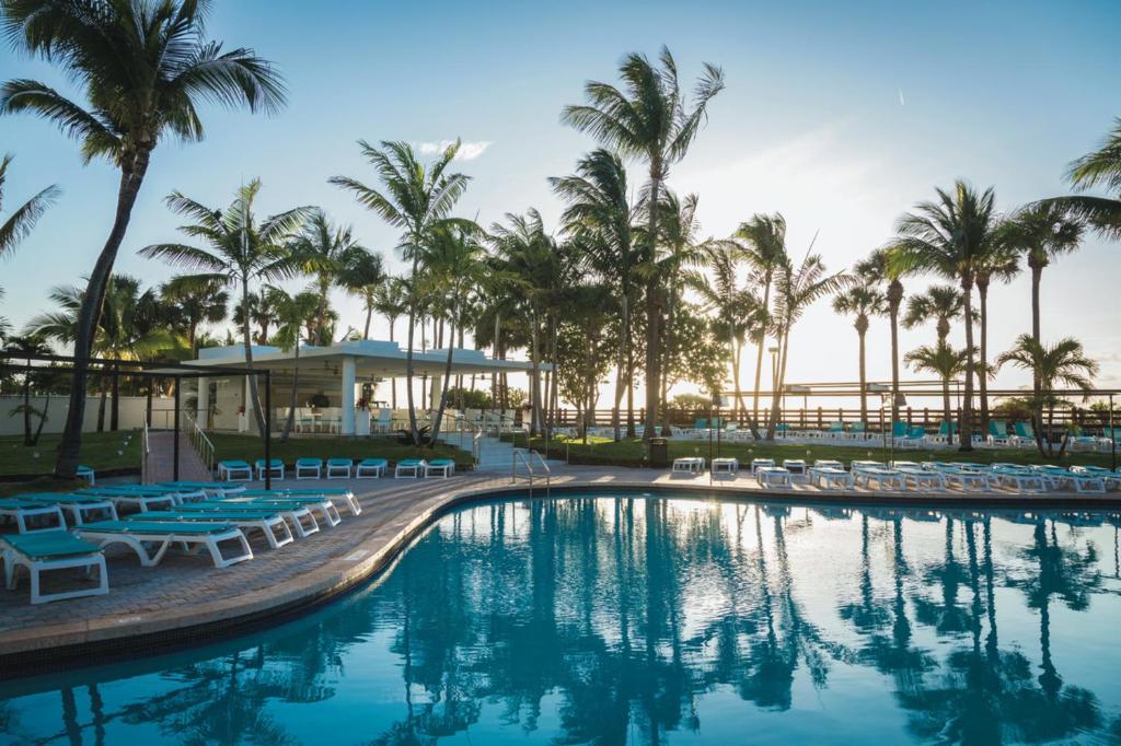 迈阿密海滩Riu Plaza Miami Beach的一个带椅子和棕榈树的度假村游泳池