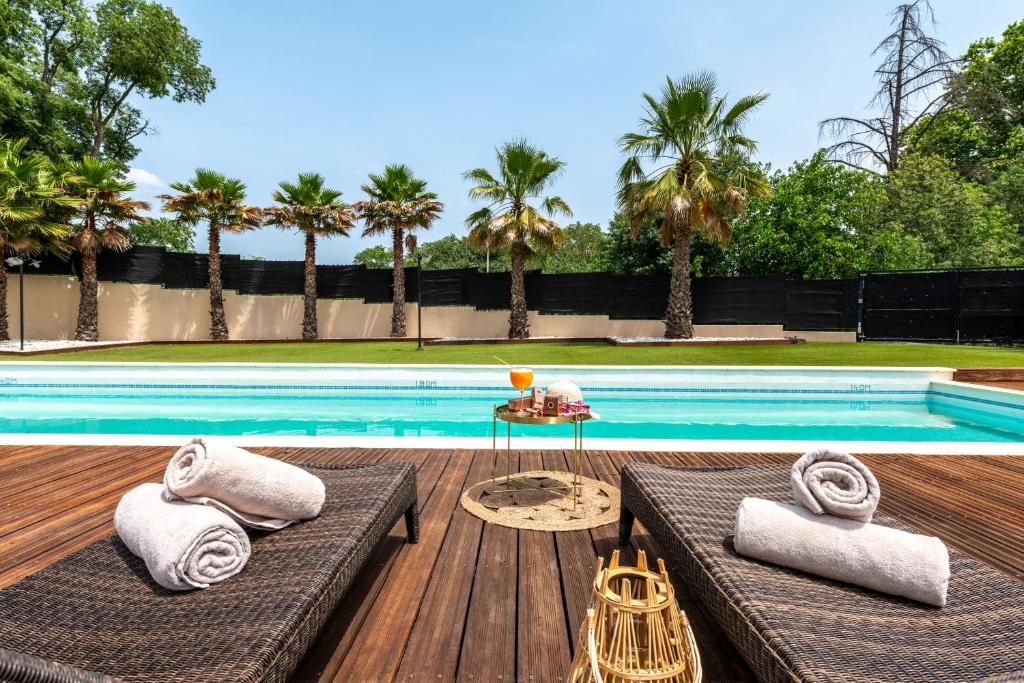 蒙彼利埃Zenitude Hotel la Valadiere, Ascend Hotel Collection的游泳池旁设有2个长椅和1张桌子