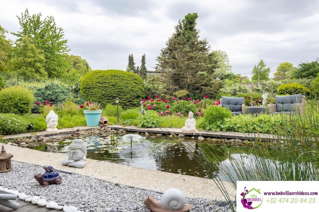 BassengeB&b La Villa Orchidées, breakfast included的花园四周设有池塘和雕像