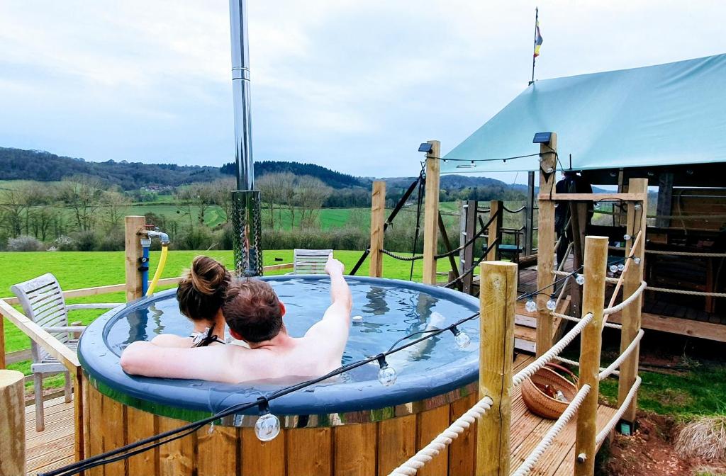Shelsley WalshHakuna Matata Safari Lodge - Sublime, off-grid digital detox with hot tub的坐在热水浴缸中的男人和女人
