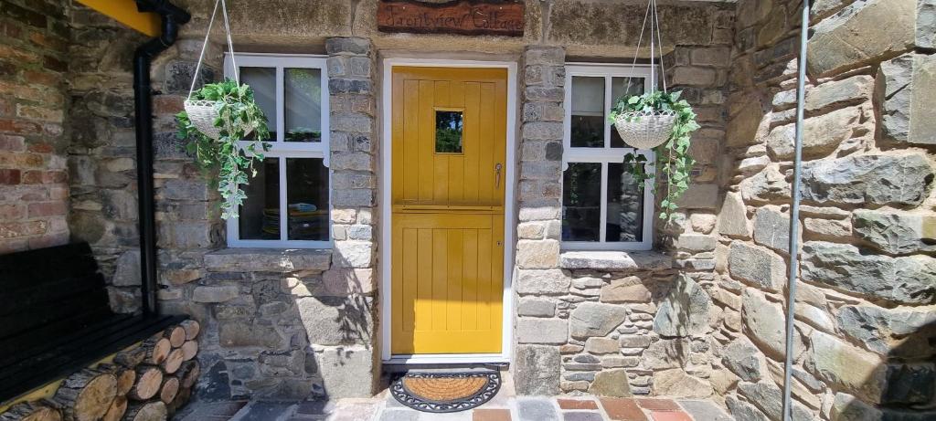 BallynahinchFrontview Cottage - Sleeps 6的石头房子的黄色门,有两扇窗户