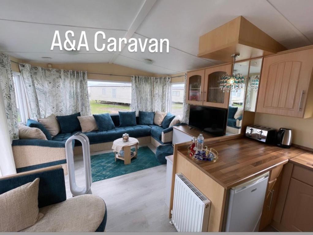 滨海莱斯当A&A Caravan Holidays的厨房以及带沙发和桌子的客厅。