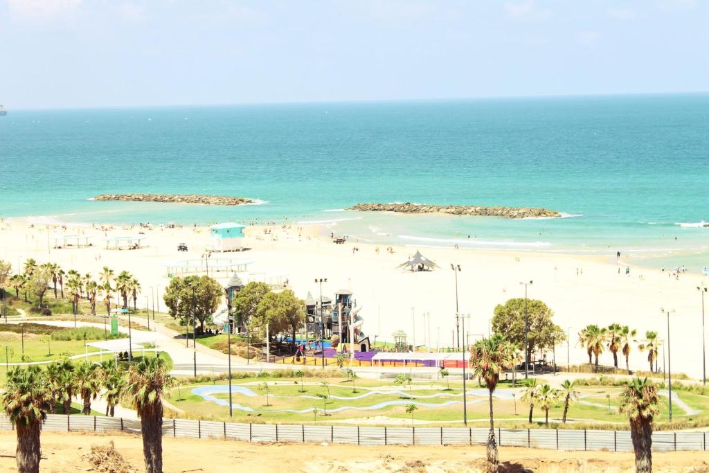 亚实基伦Best Beach View, Gym, Massage Chair, Low Fee For Off-Site Indoor Pool, Spa & Breakfast נוף ים מאלף, כיסא מסאז, חדר כושר, אפשרות לארוחת בוקר כשר, בריכה מקורה, וספא בתשלום ממש מוזל的海滩上种有棕榈树和人