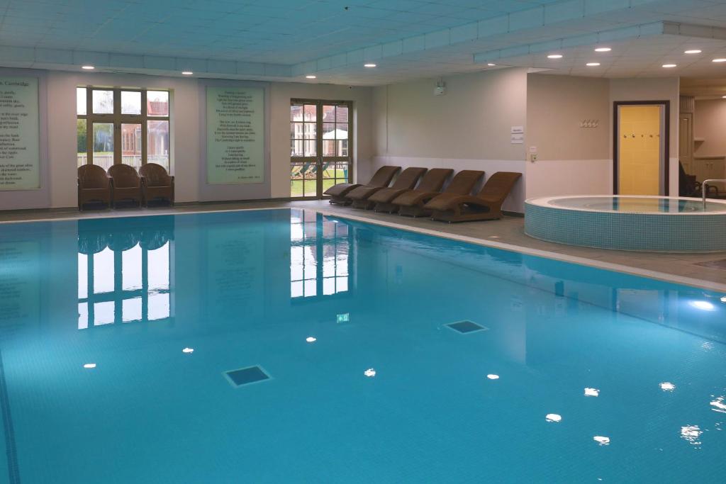 剑桥Cambridge Belfry Hotel & Spa的大楼内带椅子的大型游泳池