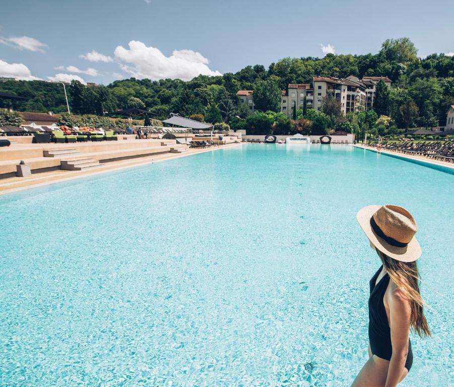 里昂里昂大都会酒店的站在游泳池前戴帽子的女人