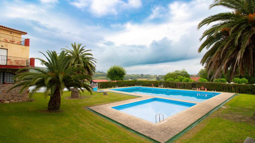 桑提亚纳德玛Resort Camping Santillana del Mar的棕榈树庭院内的游泳池