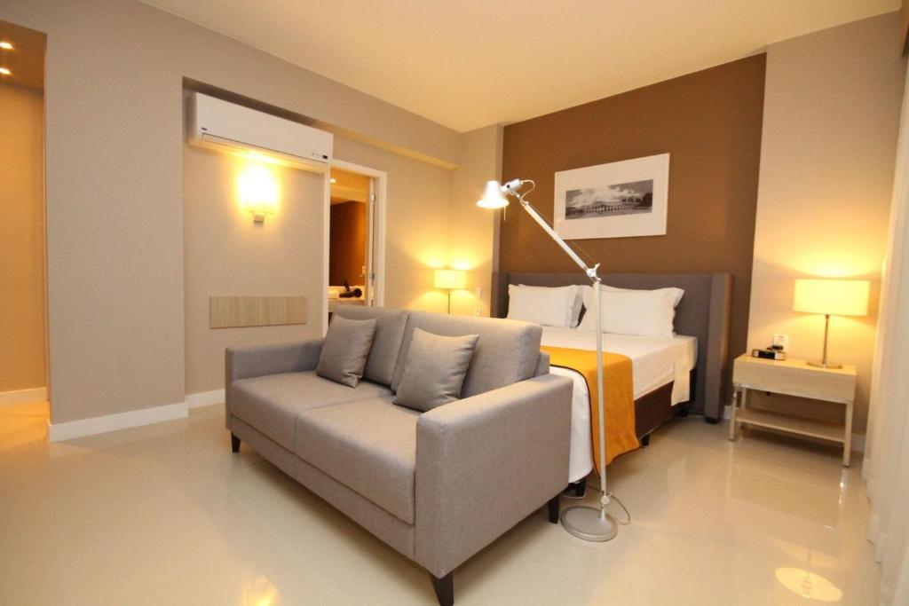 里约热内卢Linda suíte de hotel Harry的一间带沙发、床和灯的卧室