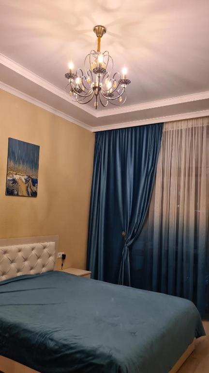 乔克-塔尔Иссык-Куль Кыргызстан, коттедж ЦО Палм Бич的一间卧室配有蓝色的床和吊灯。