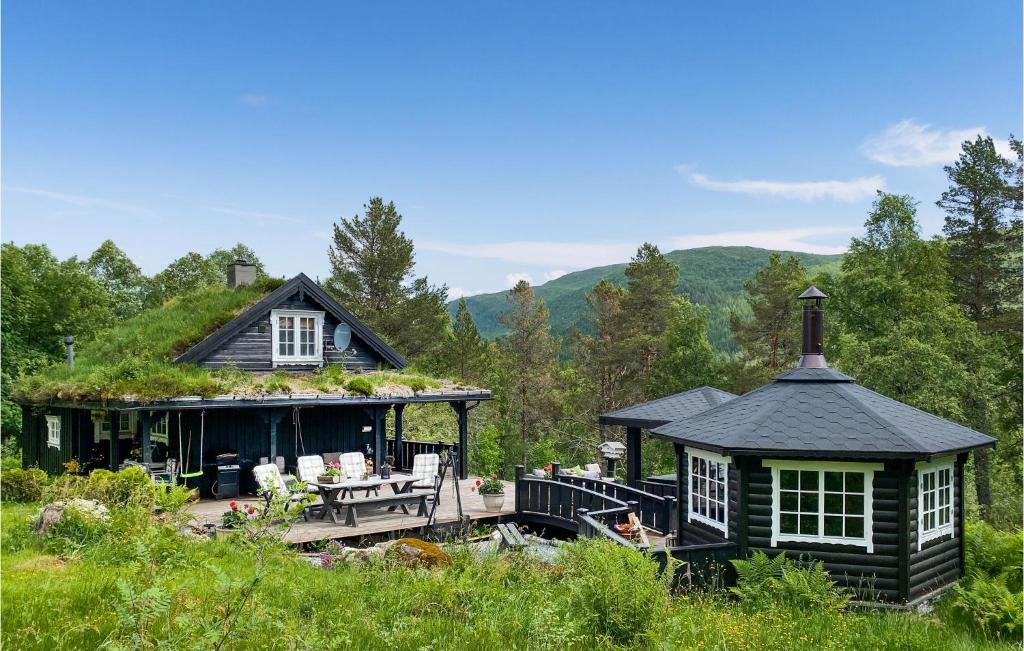 莫尔德Stunning Home In Molde With Kitchen的黑色房子,设有草屋顶,配有桌子和椅子