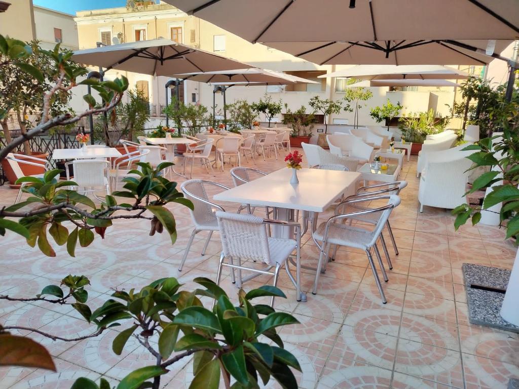 巴勒莫Hotel Trinacria的一个带桌椅和遮阳伞的庭院