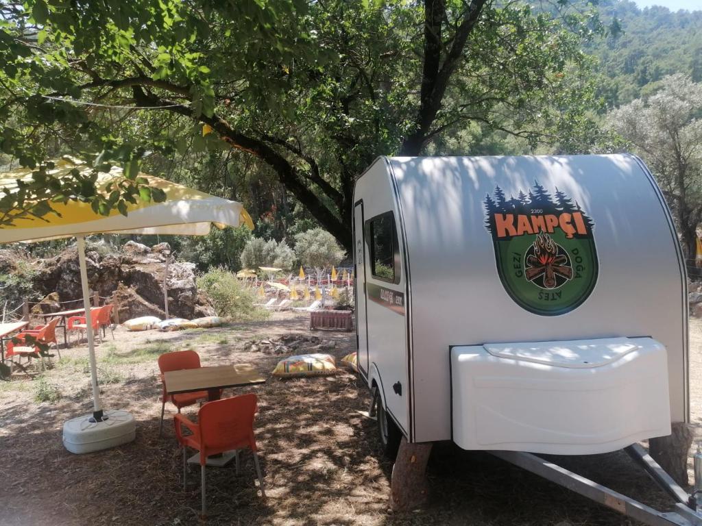 穆拉Sultaniye Camping的停在树下并带桌子的白色拖车