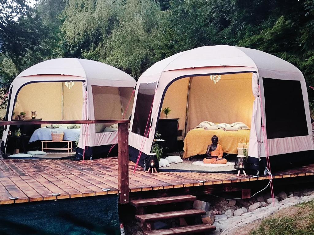 罗斯诺夫·波德·拉德霍斯滕Glamping Rožnov的两个帐篷,一个女人坐在木甲板上