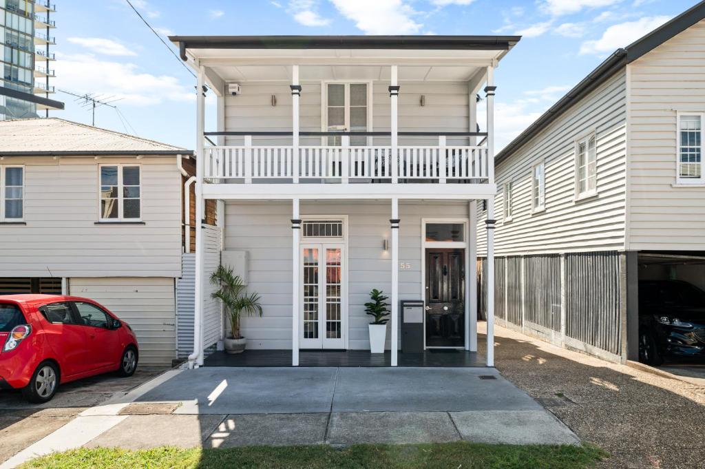 布里斯班Amelia Terrace - House in Brisbane City Central的车道上一辆红色汽车的白色房子