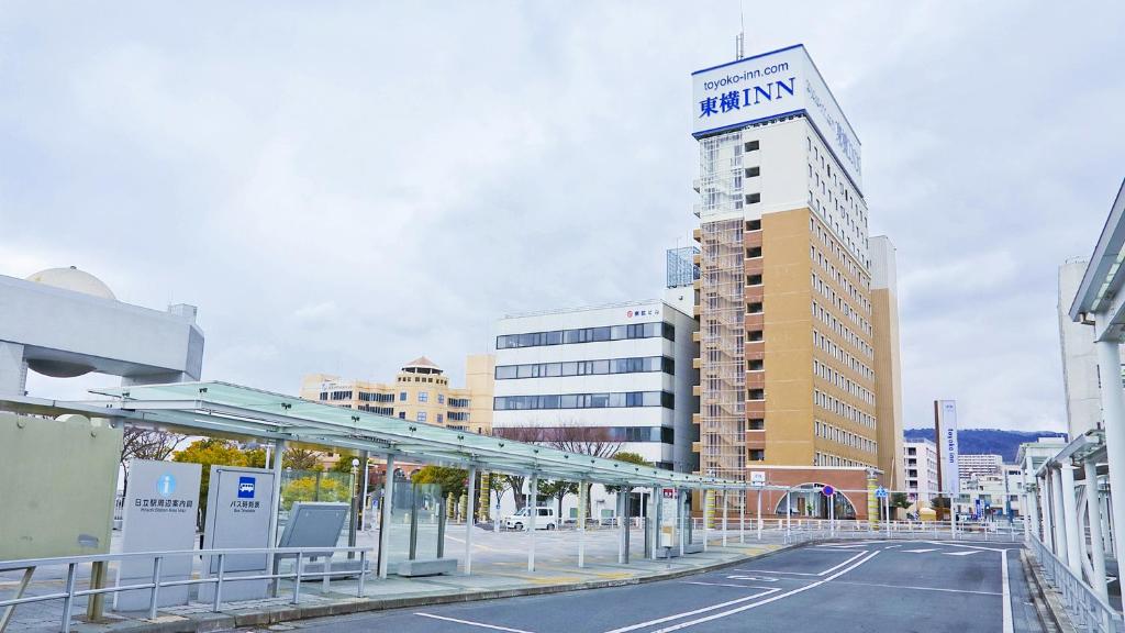 日立市Toyoko Inn Hitachi Ekimae的一座公共汽车站,在一座建筑的顶部有Aania标志