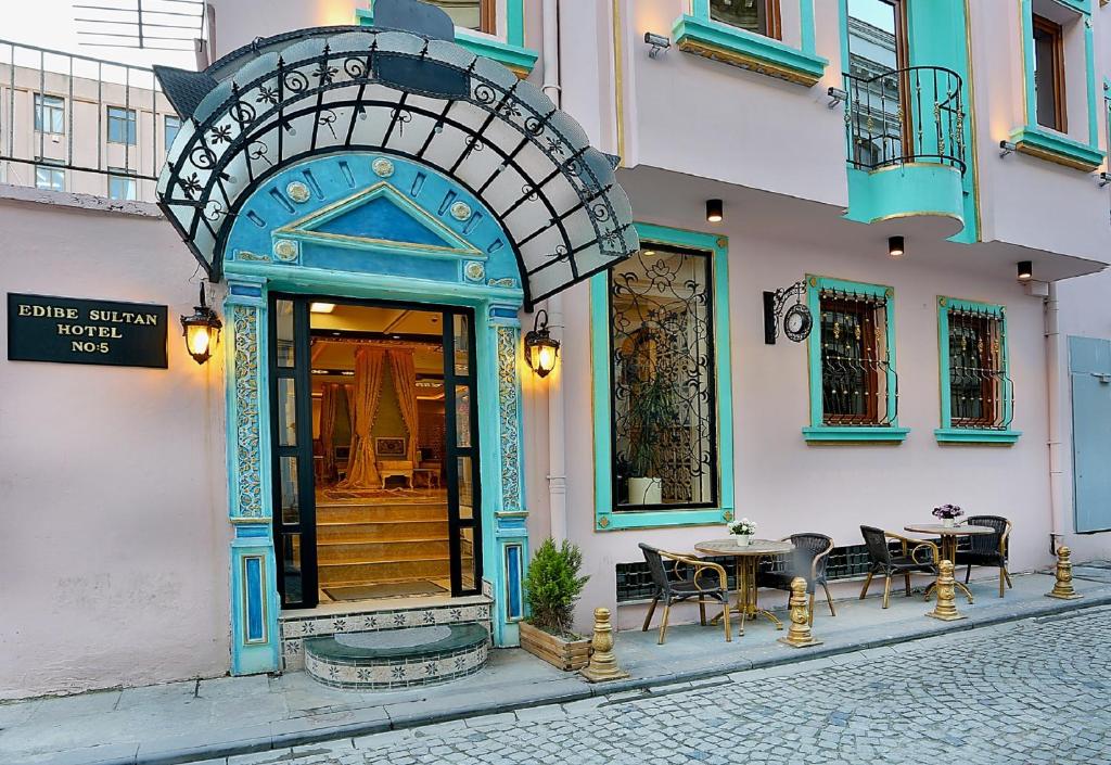 伊斯坦布尔Edibe Sultan Hotel的一座带拱形门廊的建筑,配有桌椅