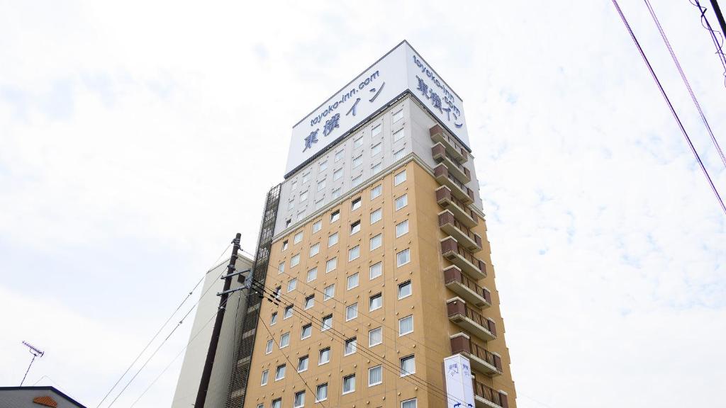 NishigoToyoko Inn Shin-shirakawa Ekimae的一座高大的建筑,上面有标志