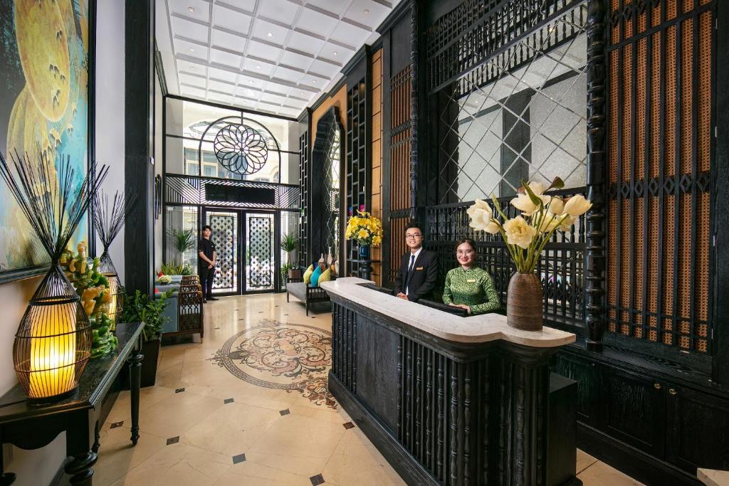 河内Scent Premium Hotel的两个人站在带柜台的大厅