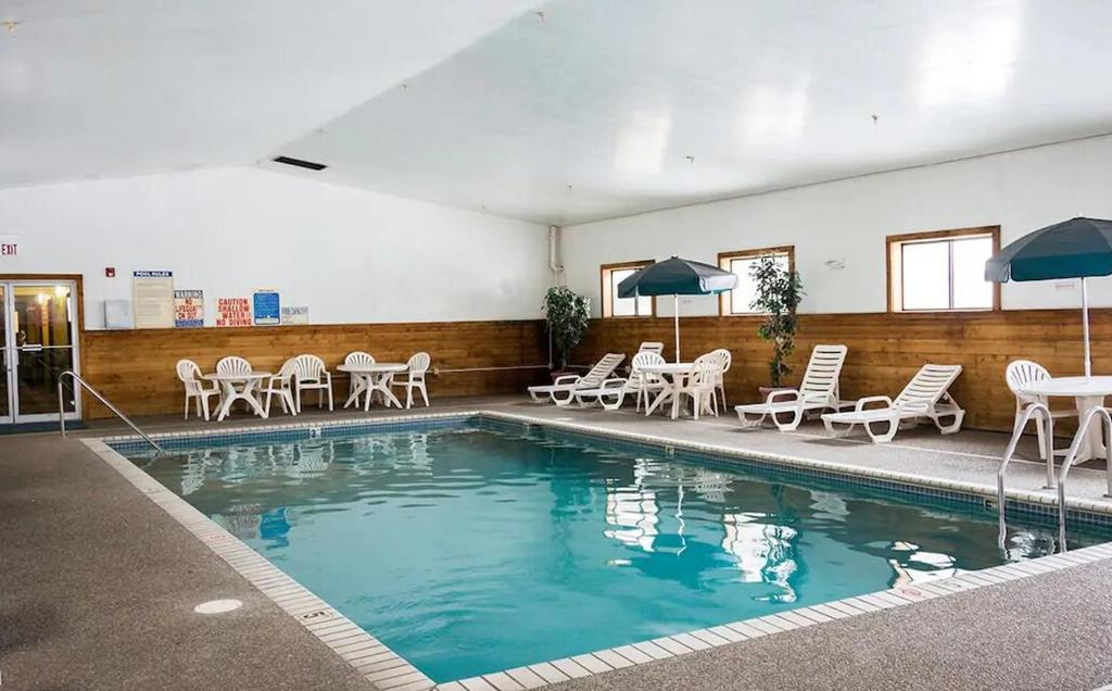 罗斯维尔Norwood Inn and Suites - Minneapolis-St Paul Roseville的一个带桌椅和遮阳伞的游泳池