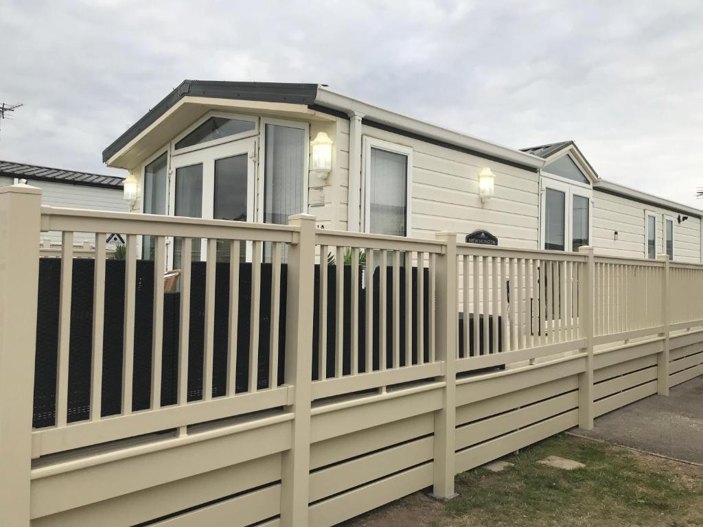 拉尔Hot Tub Accommodation North Wales Caravan的白色栅栏的房子