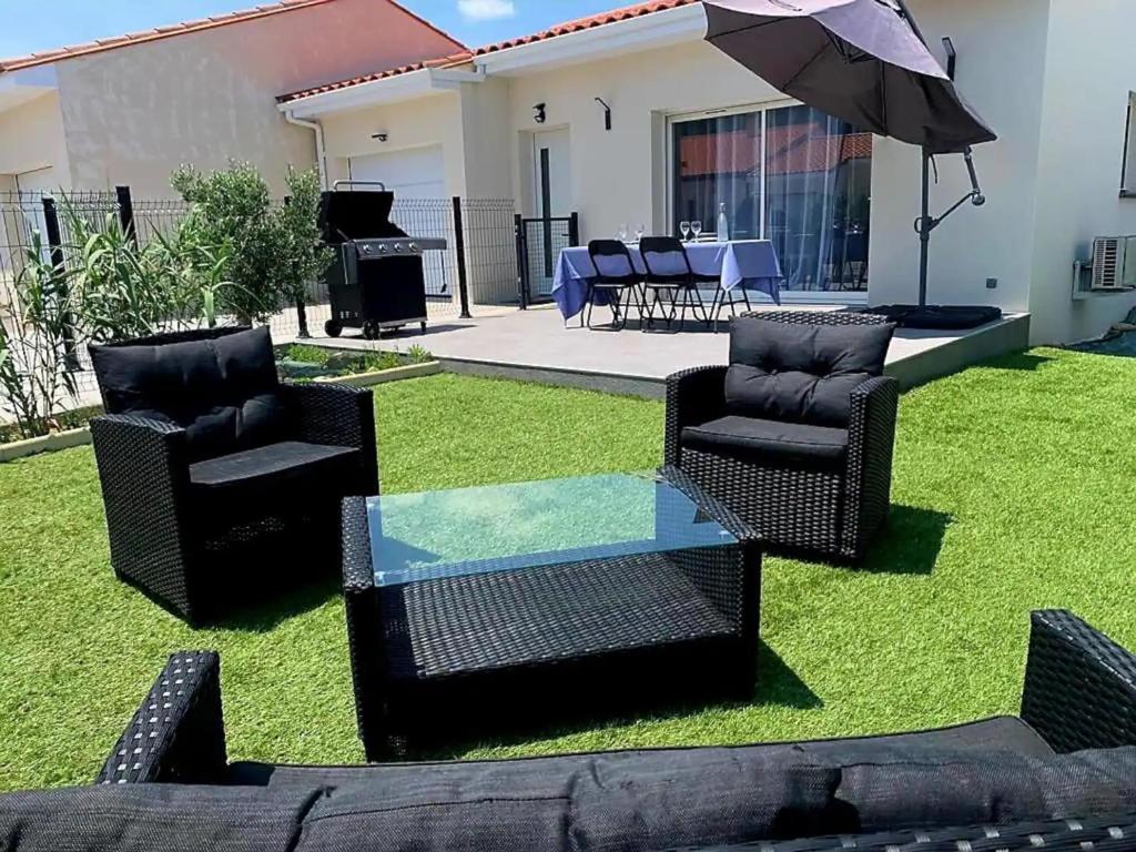 勒宝洛Le Brasil - Maison 74 m - Calme avec terrasse Sud classée 3 étoiles的庭院配有桌椅和遮阳伞。