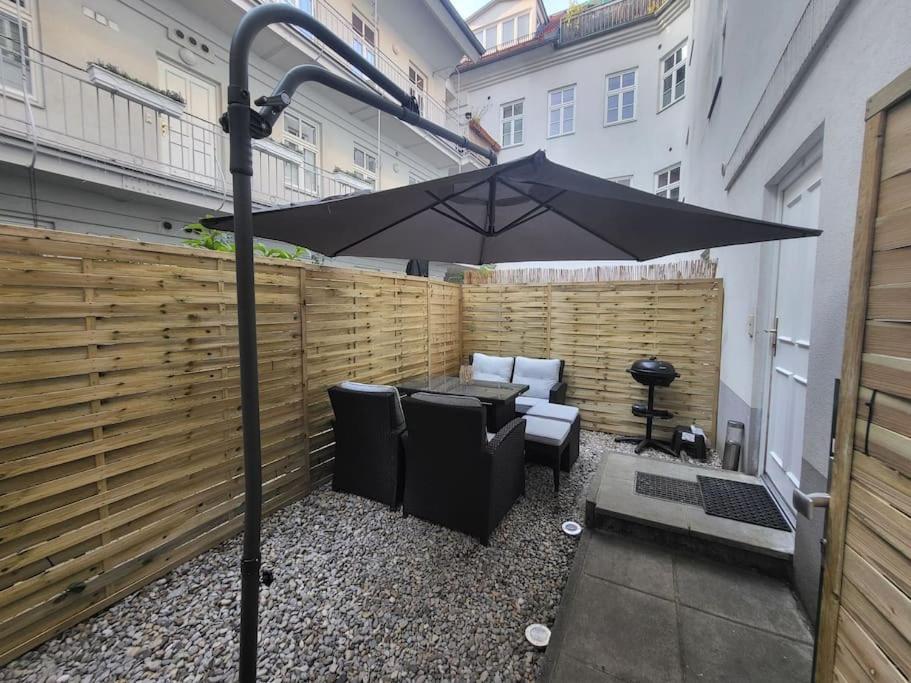 维也纳Exklusive Gartenwohnung的庭院配有遮阳伞和桌椅。
