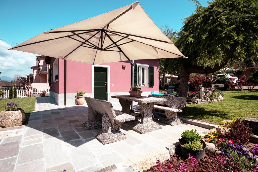 日科德尔格尔福迪艾斯La Casetta的粉红色房子前带雨伞的野餐桌