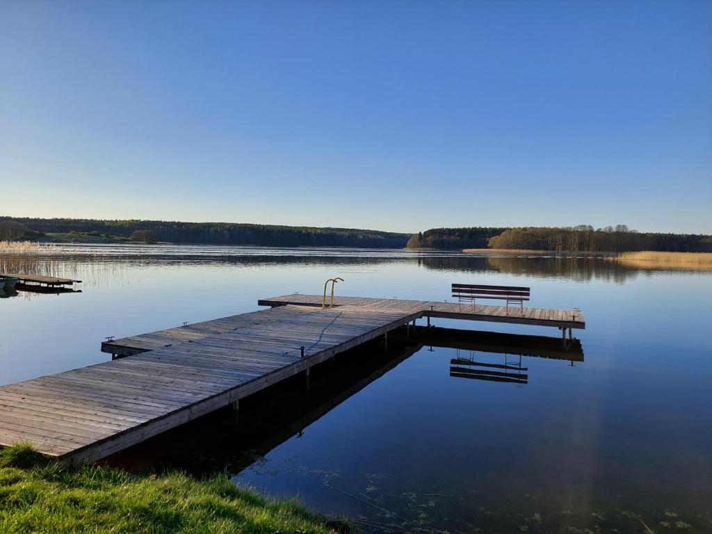 雷恩Domki nad jeziorem - Posiadłość Nad Zatoką的湖上带两个长椅的码头