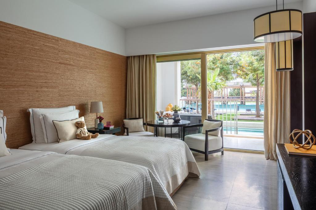 维拉摩拉Anantara Vilamoura Family Friendly的酒店客房设有一张床、一张书桌和一个大窗户。