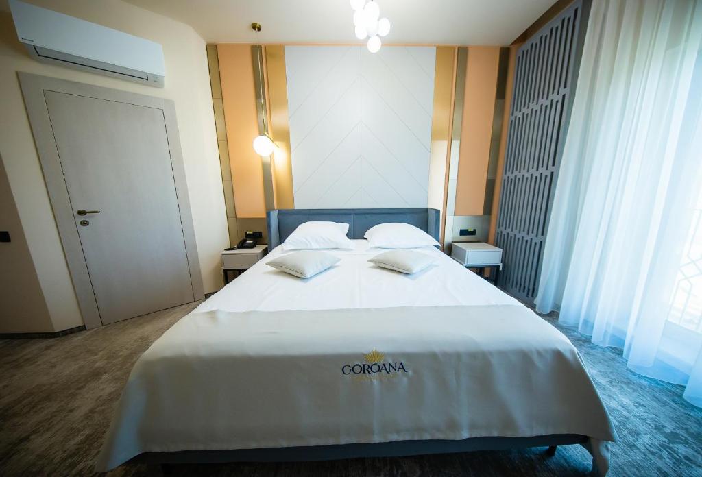 Tîrgu FrumosHotel Coroana的酒店客房带一张大床,带白色床单