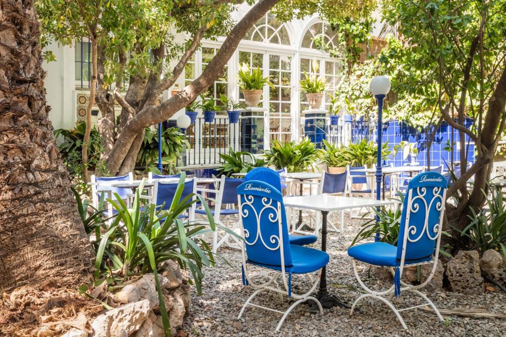 锡切斯梅迪姆浪漫酒店的花园里的一组蓝色椅子和一张桌子