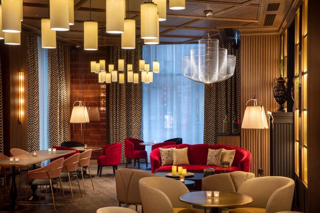 斯特拉斯堡Maison Rouge Strasbourg Hotel & Spa, Autograph Collection的餐厅设有红色的沙发和桌椅