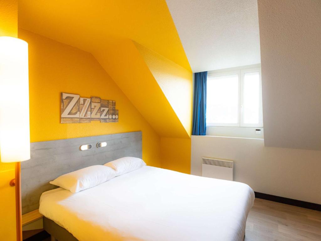 贝桑松贝桑松中心火车站宜必思快捷酒店 的黄色的卧室设有白色的床和窗户