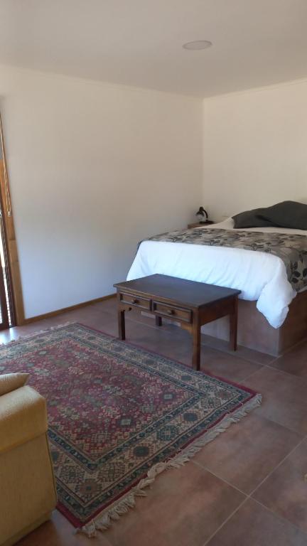 奇廉Refugio Gaia的一间卧室配有一张带桌子和地毯的床