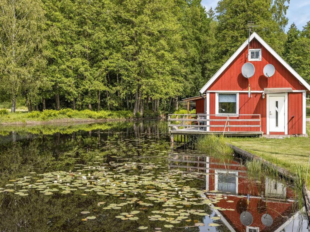 TingsrydHoliday Home Tingsmåla by Interhome的池塘中间的红房子