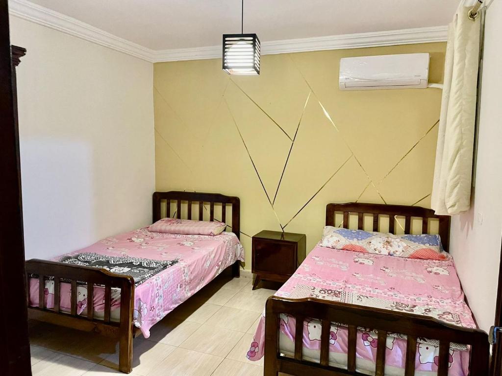 Dawwār ‘Abd al ‘Aţī Abū ‘AjūzDIMORA CHARMING CHALET的配有粉红色床单的客房内的两张床