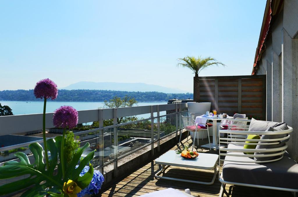 日内瓦尼维马诺特尔酒店的阳台配有桌椅,享有水景。