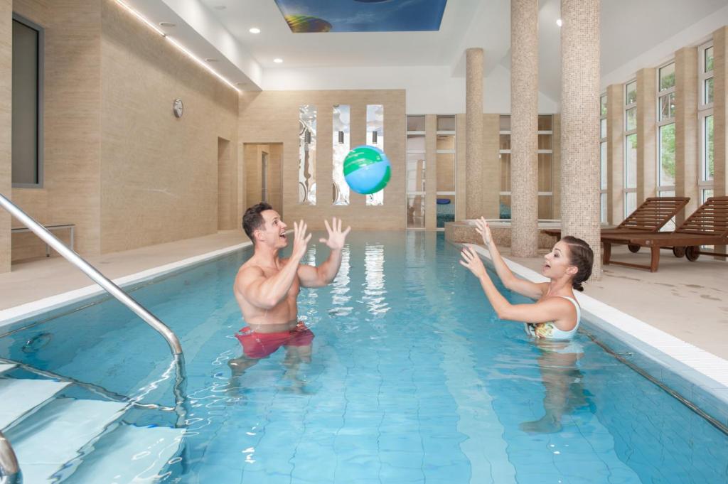 斯维诺乌伊希切瑟萨斯卡敖迪酒店的男人和女人在游泳池玩沙滩球
