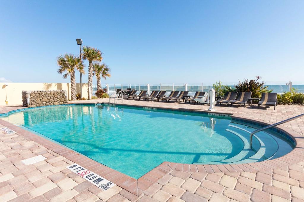 代托纳海滩代托纳海滩/海滨汉普顿酒店的一个带椅子的游泳池,背景是大海
